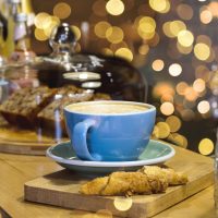 Tasty plain cup of latte on a wooden table in a coffee shop, bokeh lights on the background